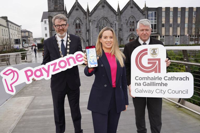 Deputy Mayor Niall McNelis, Director of Finance Helen Kilroy and Community warden Paul Quainn holding  signs and a mobile phone at the launch of the new Galway City Parking app